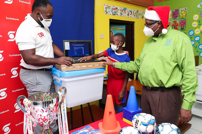 Craig Richards (left), Scotiabank May Pen branch manager examines some of the items provided for the May Pen Primary Sports department from the funds won in the 2019 CONCACAF Scotiabank Next Play football tournament. With him is Major Paul Scott (right) and a student of the school.