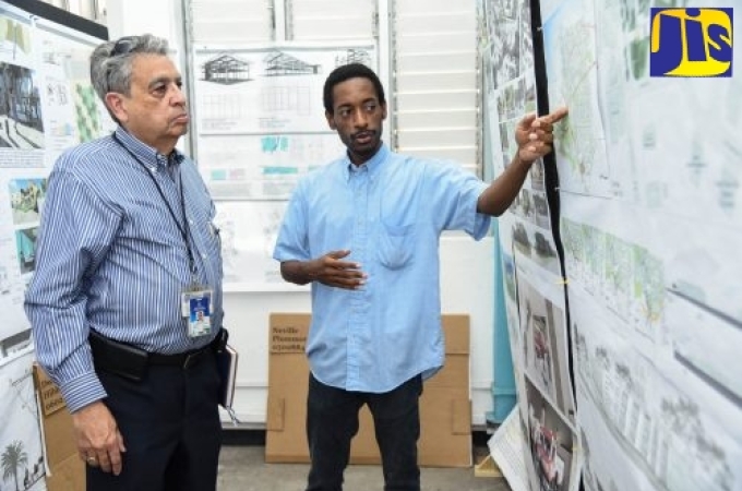 Senior Advisor and Consultant to Minister without Portfolio in the Office of the Prime Minister, Hon. Mike Henry, Bindley Sangster (left), listens with interest as Neville Plummer, Master of Architecture student at the University of Technology (UTech) Caribbean School of Architecture (CSA), explains the concept behind his final-year project. Occasion was a visit by the Core Implementation Team of the Vernamfield Development project to the school during its 30th anniversary exhibition. (JIS Photo)
