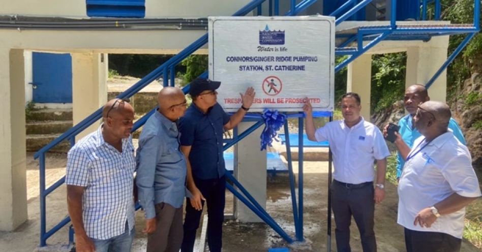 Senator Matthew Samuda (centre right) and Dr Christopher Tufton, Member of Parliament, St Catherine West Central (centre left) points to the signboard following the commissioning of the Connors/Ginger Ridge Water Supply System in the community on October 11, 2023. (Jay Nansense Photo)