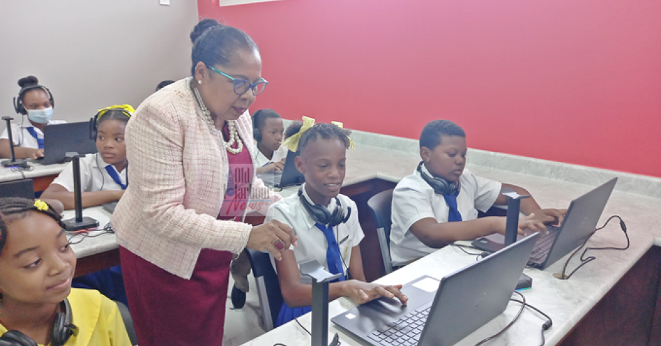 Custos of St Catherine Icylin Golding engages a student inside the US$50,000 ICT classroom at Old Harbour Primary. (OH News Photo)