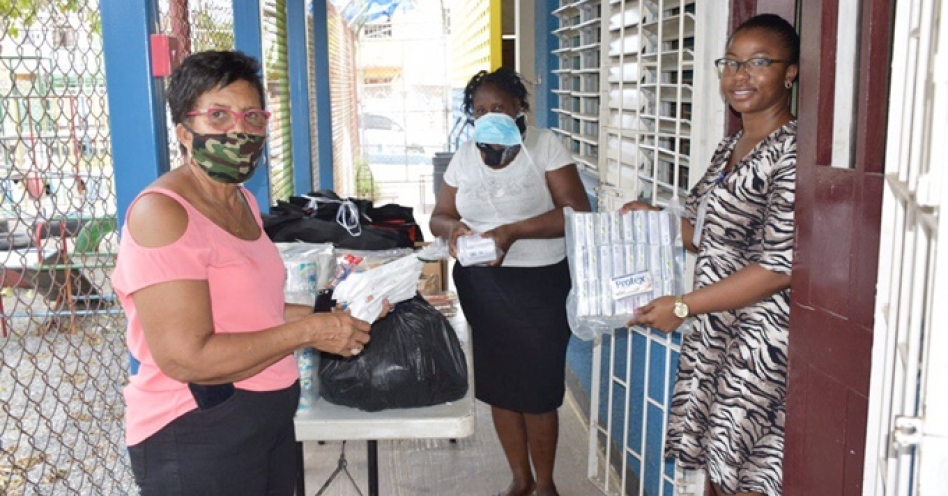 JEP CSR Committee Member/WKPP Administrative Assistant, Cherries Wiles, presents food/personal care packages to Principal of Charles Chin Loy Basic School, Veronica Sewell-Morgan, and Cook, Cynthia Lindsey.