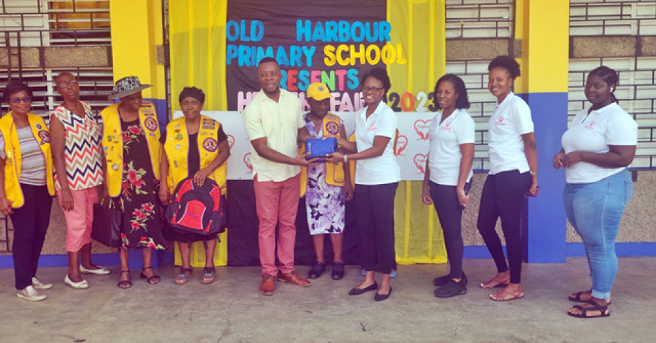 Dr Odette Thomas (centre right) presents a First Aid kit to George Goode, principal, Old Harbour Primary.
