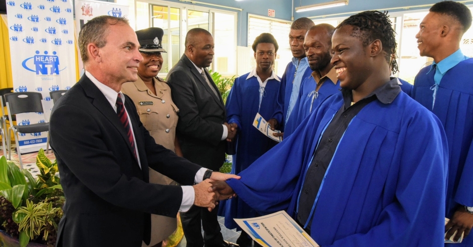 Director of the Housing, Opportunity, Production and Employment (HOPE) Programme, Colonel Martin Rickman (left), congratulates Carlton Williams, one of the 14 windscreen wipers who graduated from a Windscreen Wiper Intervention course, on Friday (November 1), at Garmex HEART Academy on Marcus Garvey Drive, in Kingston. Also congratulating the other graduates are Head of St. Andrew Central, Senior Superintendent of Police, Jacqueline Coombs (centre) and Assistant Commissioner of Police, Devon Watkiss. (JIS Photo)