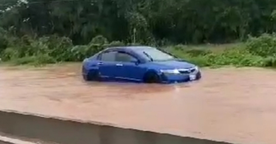 A car shuts off in flood waters from the Big Pond in Old Harbour North